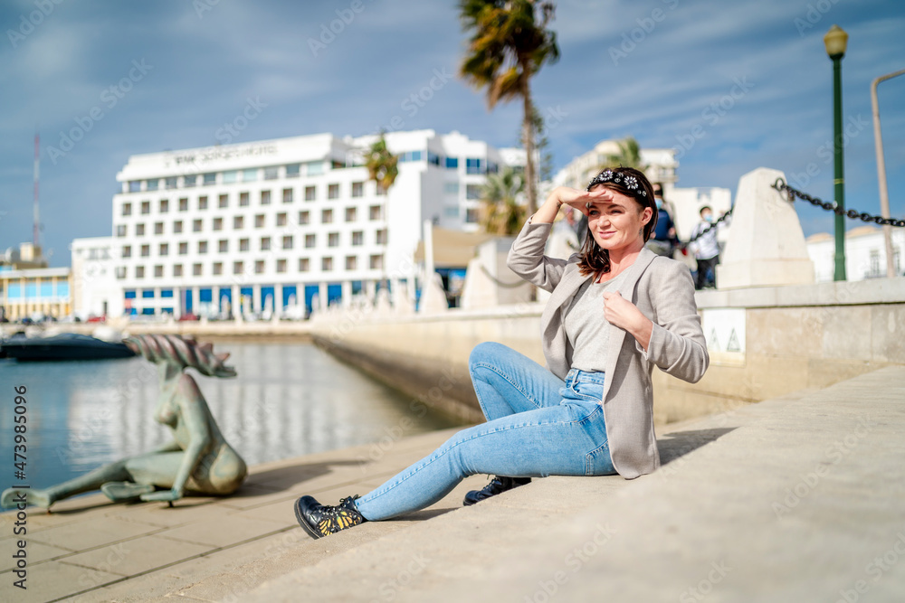 Portrait of young woman sitting by the marina