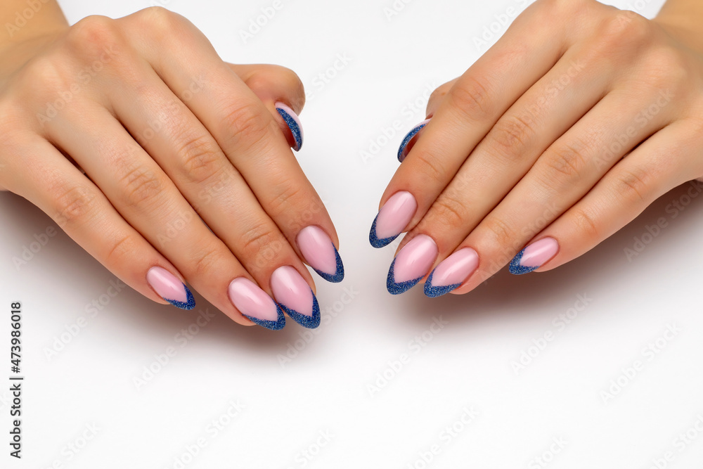 New Year's manicure. French manicure with reflective blue sequins on long sharp nails close-up on a white background. New Year's manicure. French manicure with reflective blue sequins on long sharp nails close-up on a white background.