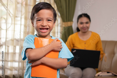 cute asian boy accompanying his mother working