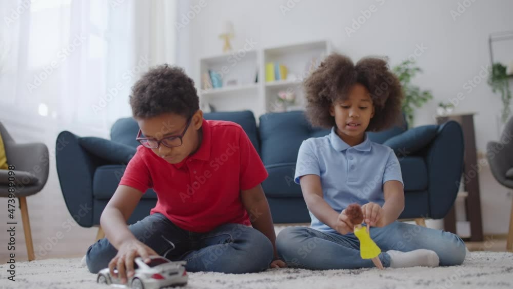African american boy and girl playing with toy car and doll at home ...