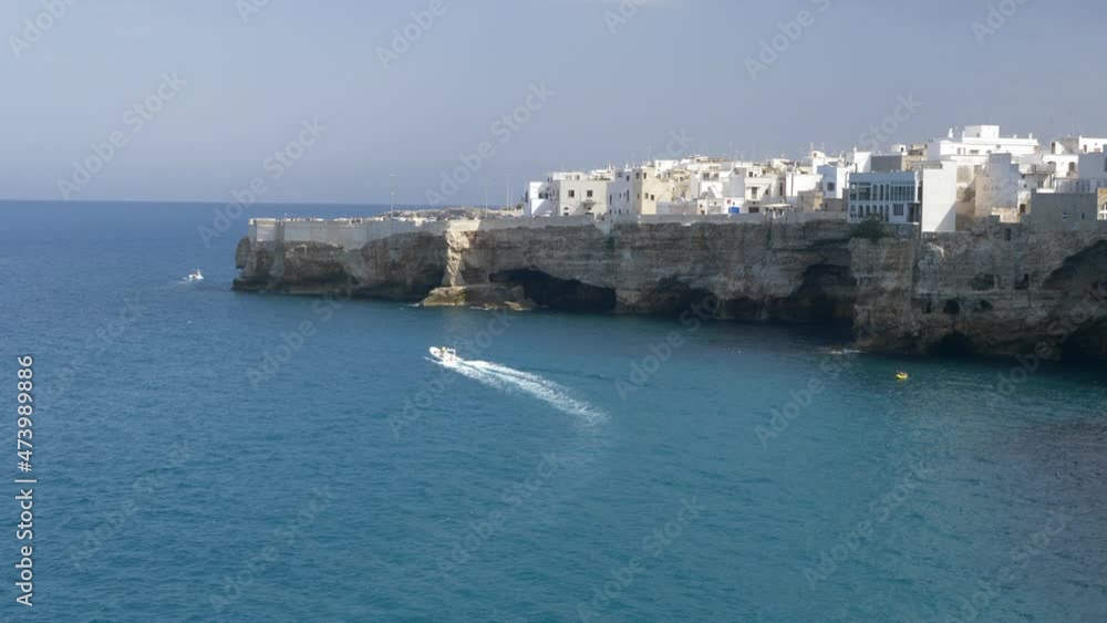 Slow Motion Of A Boat Sailing Across The Adriatic Sea With View Of Buildings On Cliff In Polignano a Mare, Italy. wide 4k Slow Motion Of A Boat Sailing Across The Adriatic Sea With View Of Buildings On Cliff In Polignano a Mare, Italy. wide 4k