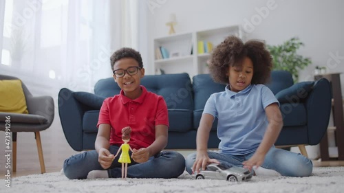 Black girl and boy playing doll and car, breaking gender stereotyping in toys