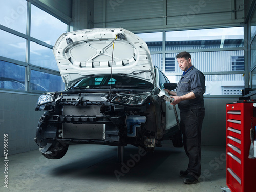 Mature expert installing car parts at auto repair shop