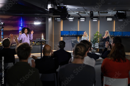 TV show host waving towards audience photo