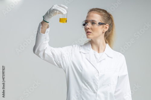 Chemical test tubes and flasks with petroleum products, the girl is a laboratory assistant, safety glasses