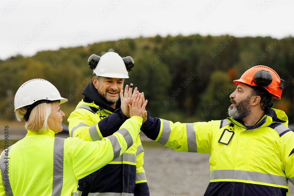 Engineers in reflective clothing high fiving Engineers in reflective clothing high fiving
