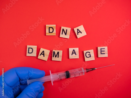 Omicron variant displaces Delta. Emergence of new dangerous strain of coronavirus COVID-19 Omicron. Syringe. Words DNA damage on colored red background photo