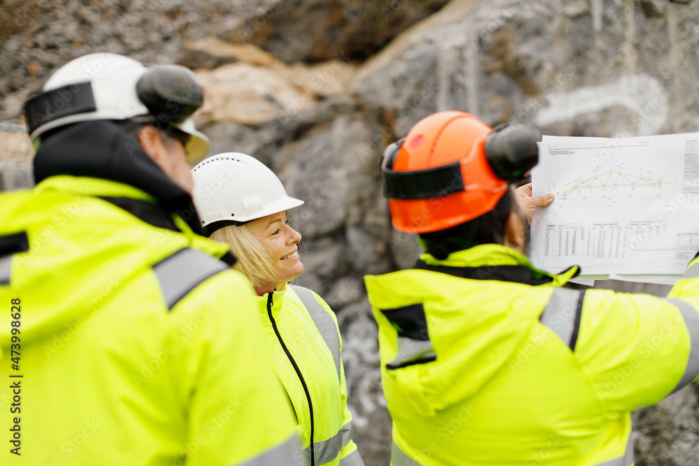 Engineers in reflective clothing discussing plans Engineers in reflective clothing discussing plans