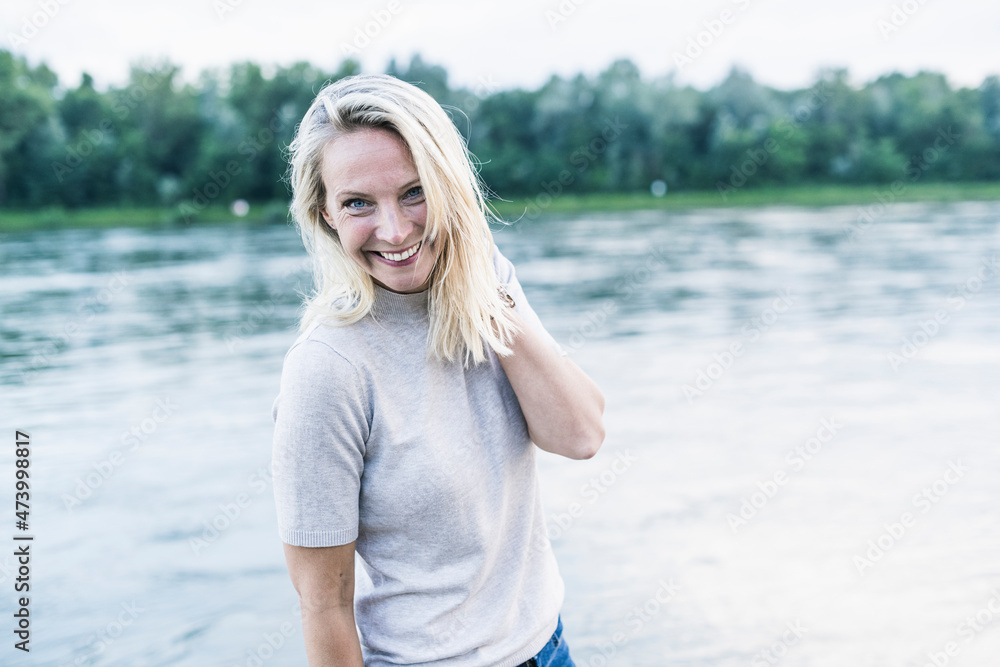 Blond woman smiling while standing by river