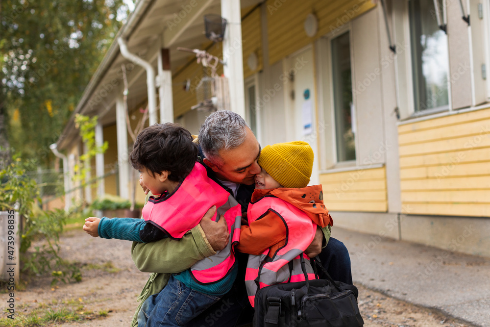 Father hugging children while collecting from school Father hugging children while collecting from school