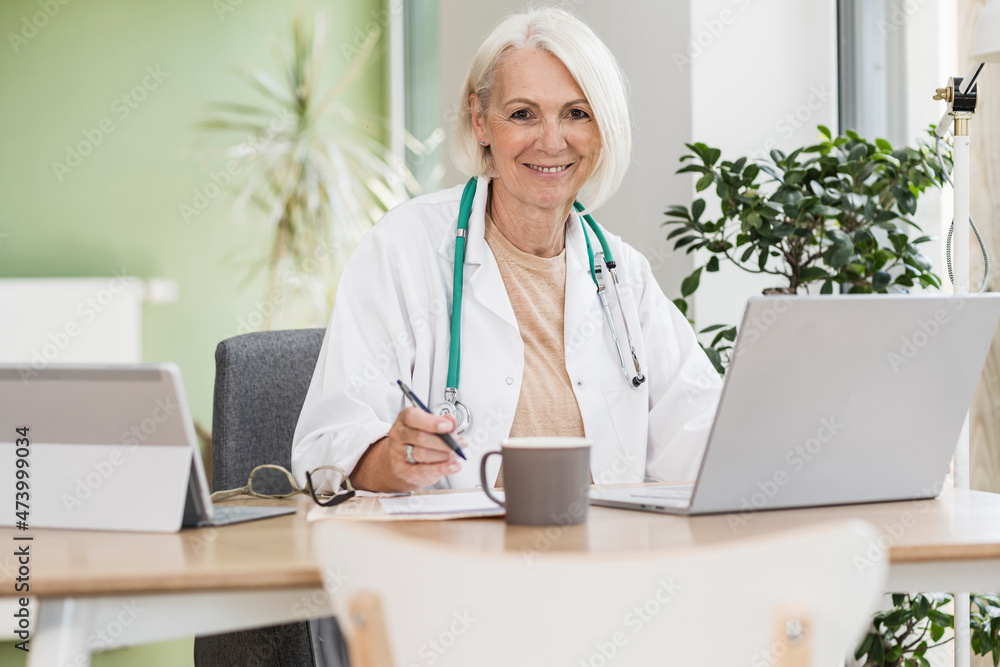 Smiling mature female doctor at desk
