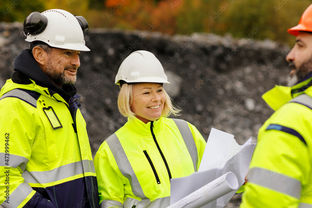 Engineers in reflective clothing looking at plans Engineers in reflective clothing looking at plans
