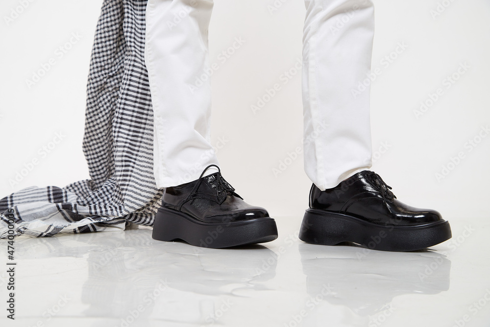 Black female or male patent leather shoes on legs of woman. Shooting for a catalog or an online store. A pair of shoes Black female or male patent leather shoes on legs of woman. Shooting for a catalog or an online store. A pair of shoes