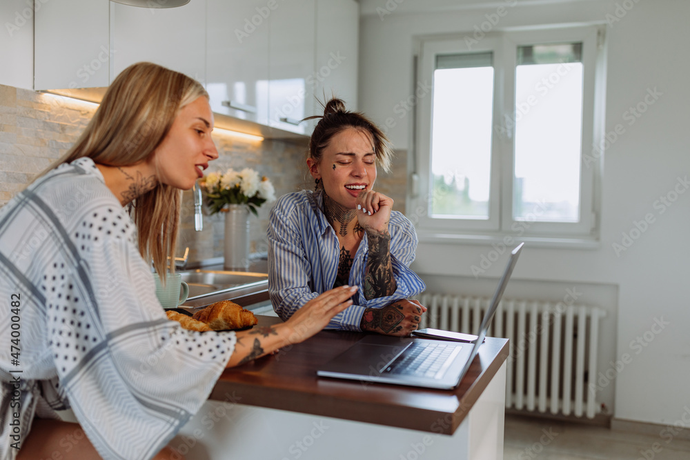 Cute lesbian couple using laptop together at home Cute lesbian couple using laptop together at home