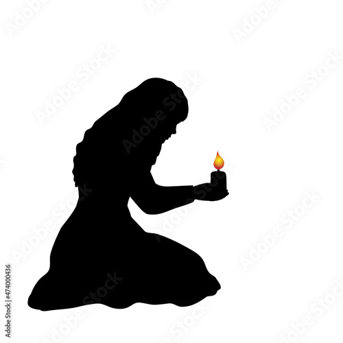 Silhouette of woman sitting on her knees with candle.