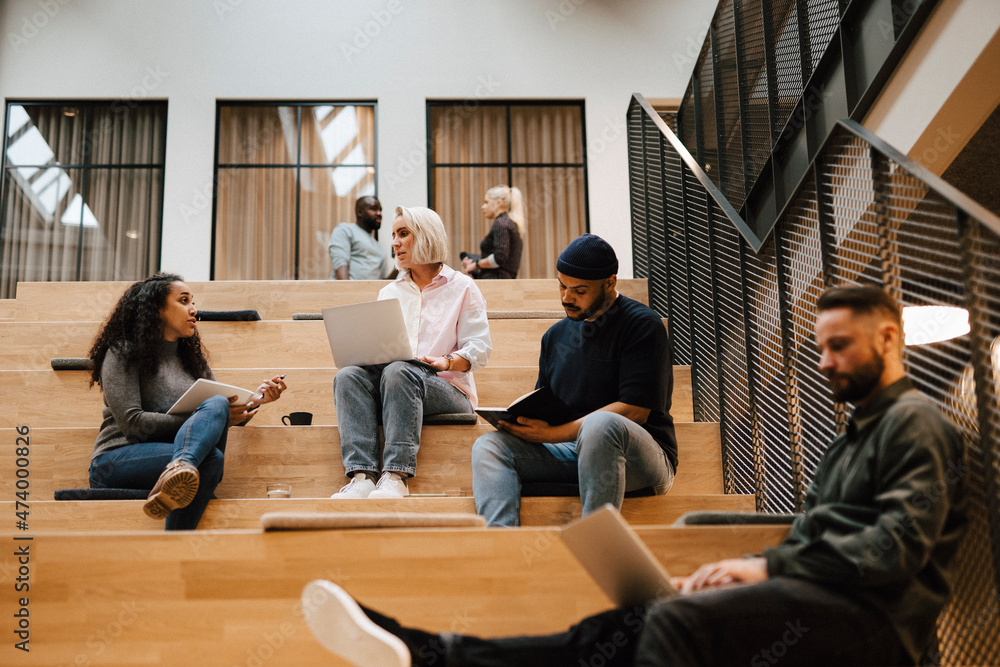 People relaxing on stairs in office building People relaxing on stairs in office building