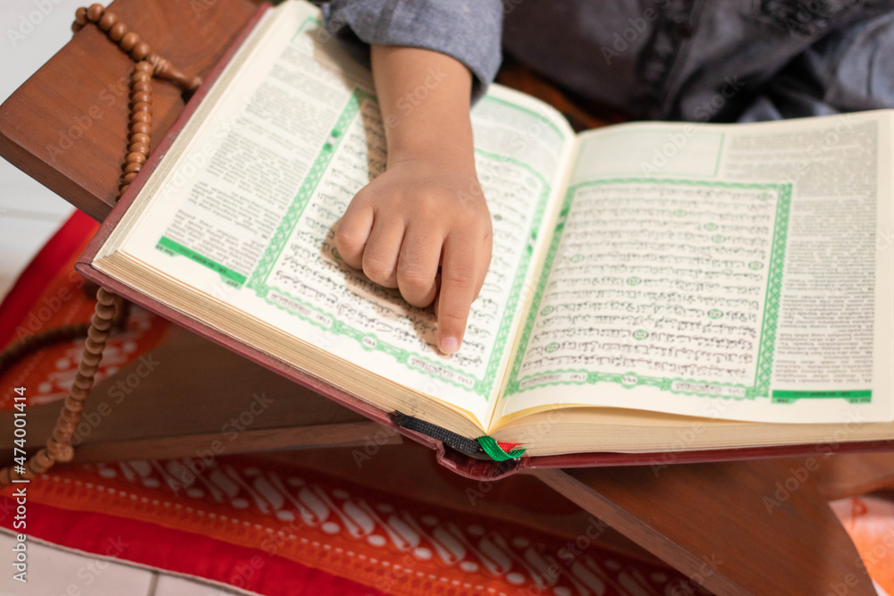 Naklejka premium Asian boy who learns to read Al-Qur'an