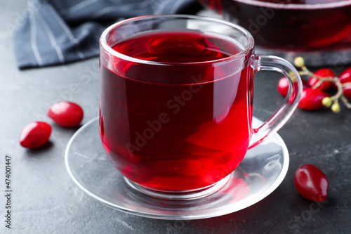 Glass cup of fresh dogwood tea and berries on black table, closeup