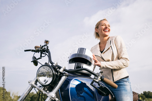 Happy female biker on motorcycle looking away photo