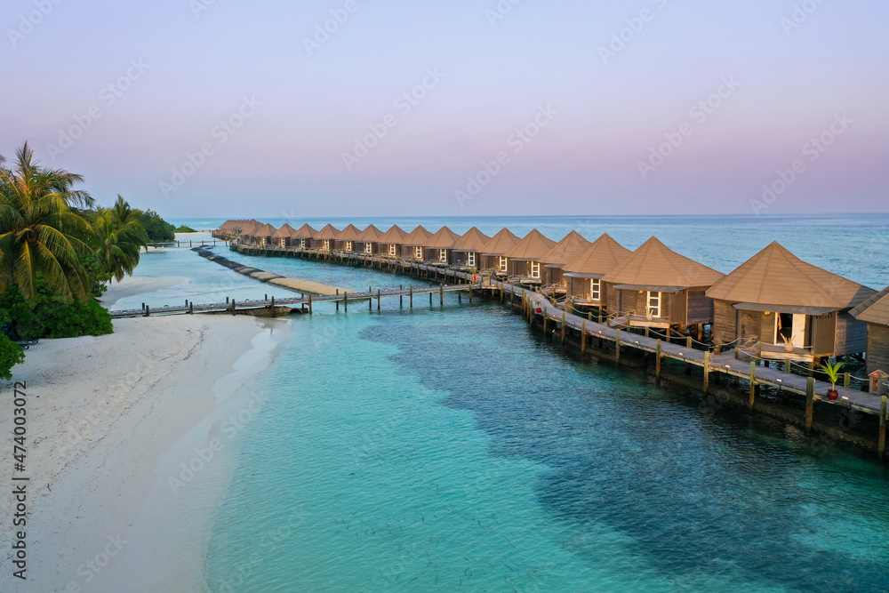 Maldives, Lhaviyani Atoll, Kuredu, Aerial view of row of coastal bungalows at dawn Maldives, Lhaviyani Atoll, Kuredu, Aerial view of row of coastal bungalows at dawn