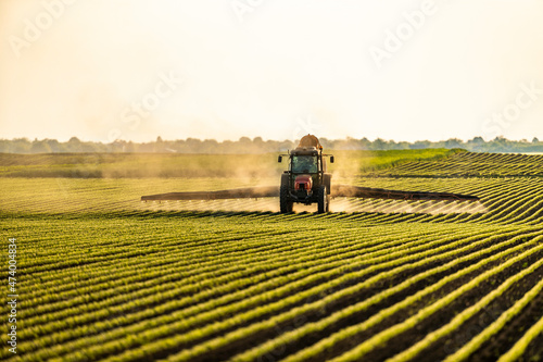 Tractor spraying soybean crops at sunset photo