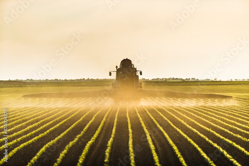 Tractor spraying soybean crops at dusk photo