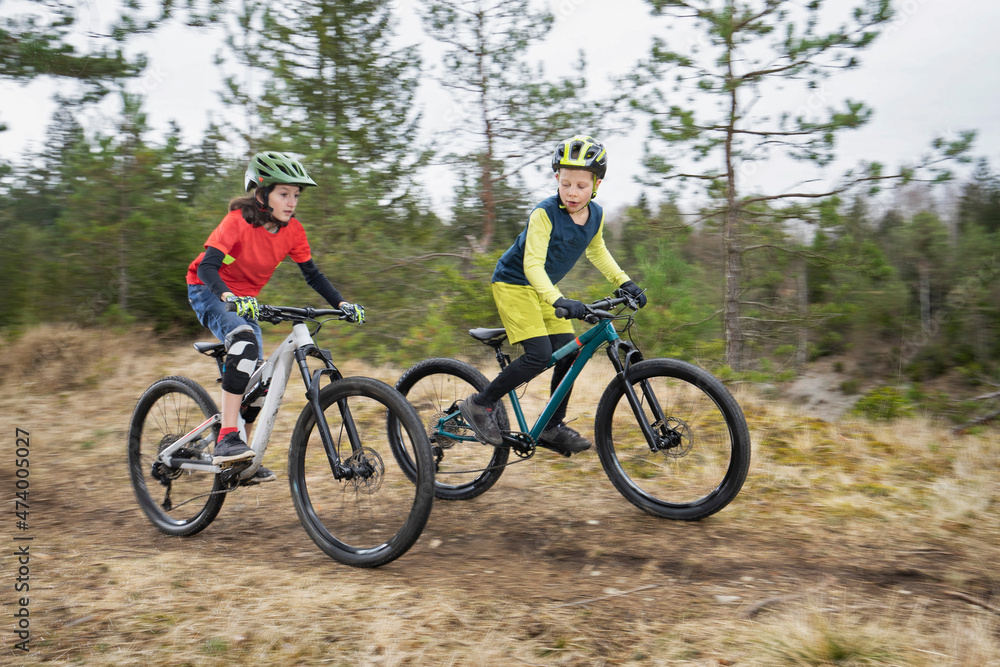 Brothers riding bicycle on dirt road in forest Brothers riding bicycle on dirt road in forest