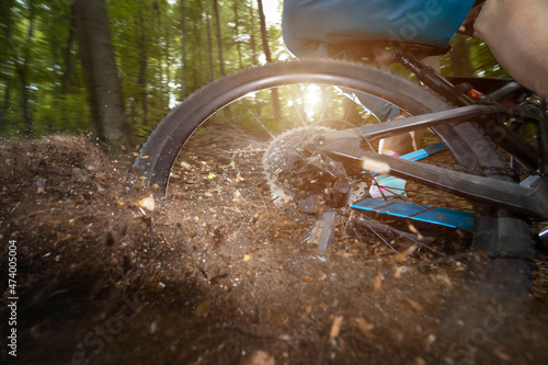 Rear wheel of bicycle drifting in dirt road at forest photo