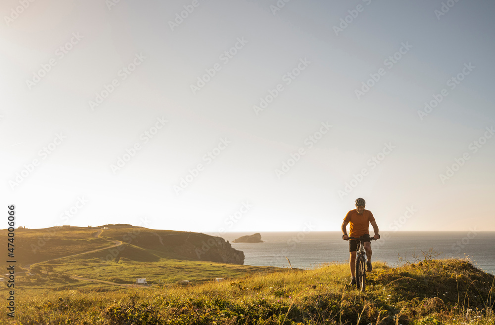 Male athlete riding bicycle on green landscape by sea Male athlete riding bicycle on green landscape by sea