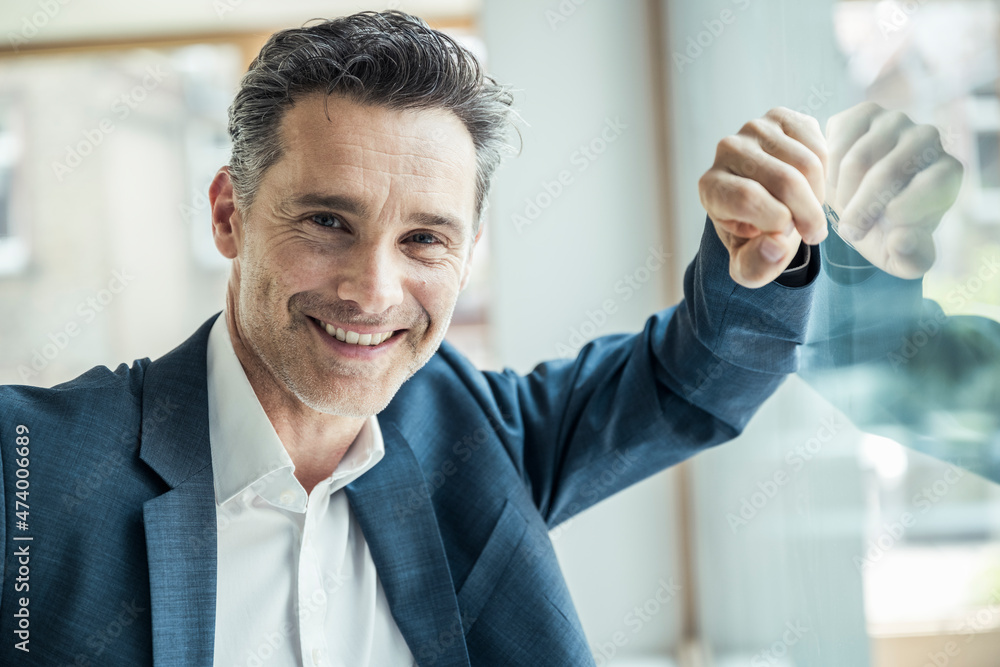 Smiling businessman leaning on office window Smiling businessman leaning on office window