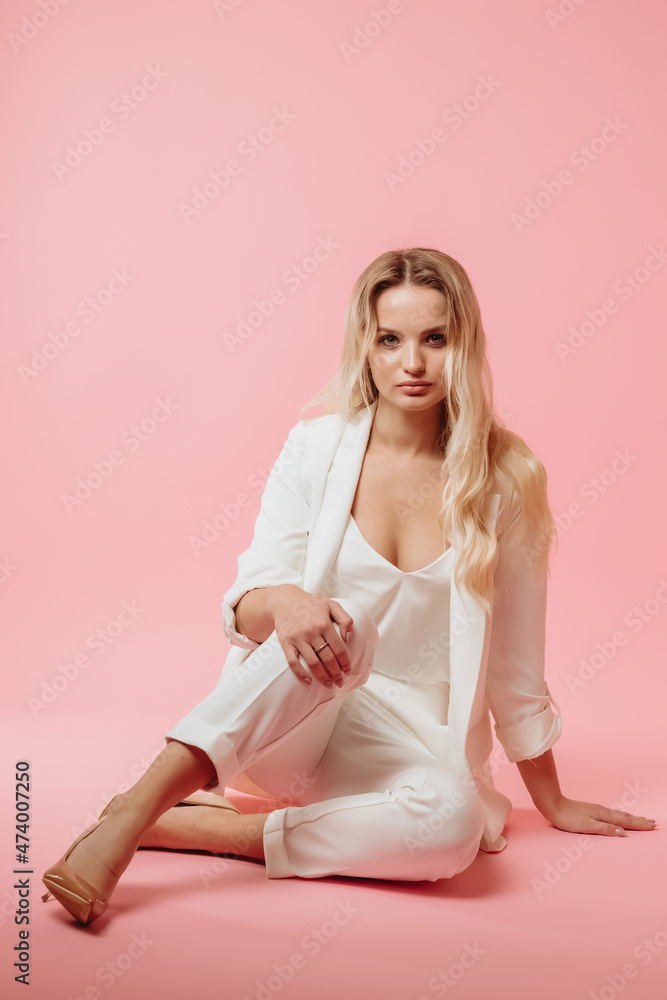 beautiful girl in a white suit on a pink background
