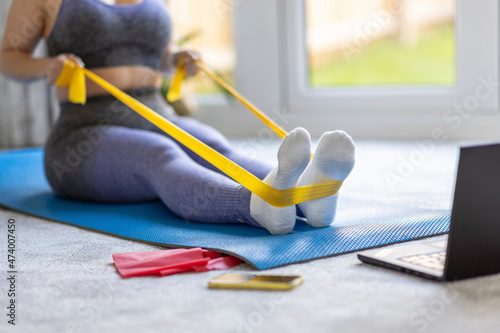 Mid adult woman practicing stretching exercise with resistance band at home