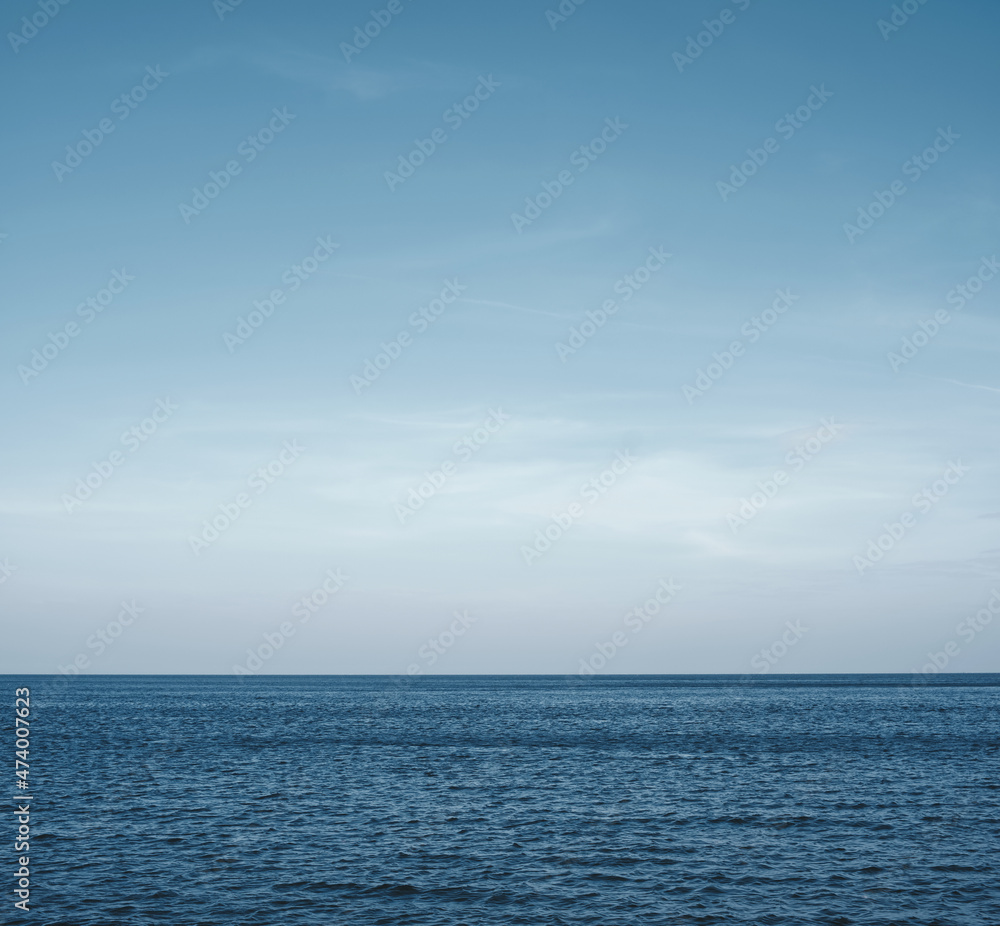 Calm sea waves against the horizon with a deep blue sky backdrop. Seascape background. The tranquility of nature. The vast ocean.