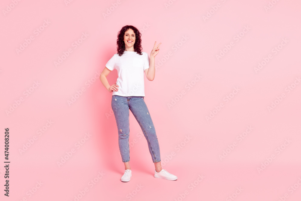 Full length photo of young woman show fingers peace cool v-symbol isolated over pink color background Full length photo of young woman show fingers peace cool v-symbol isolated over pink color background