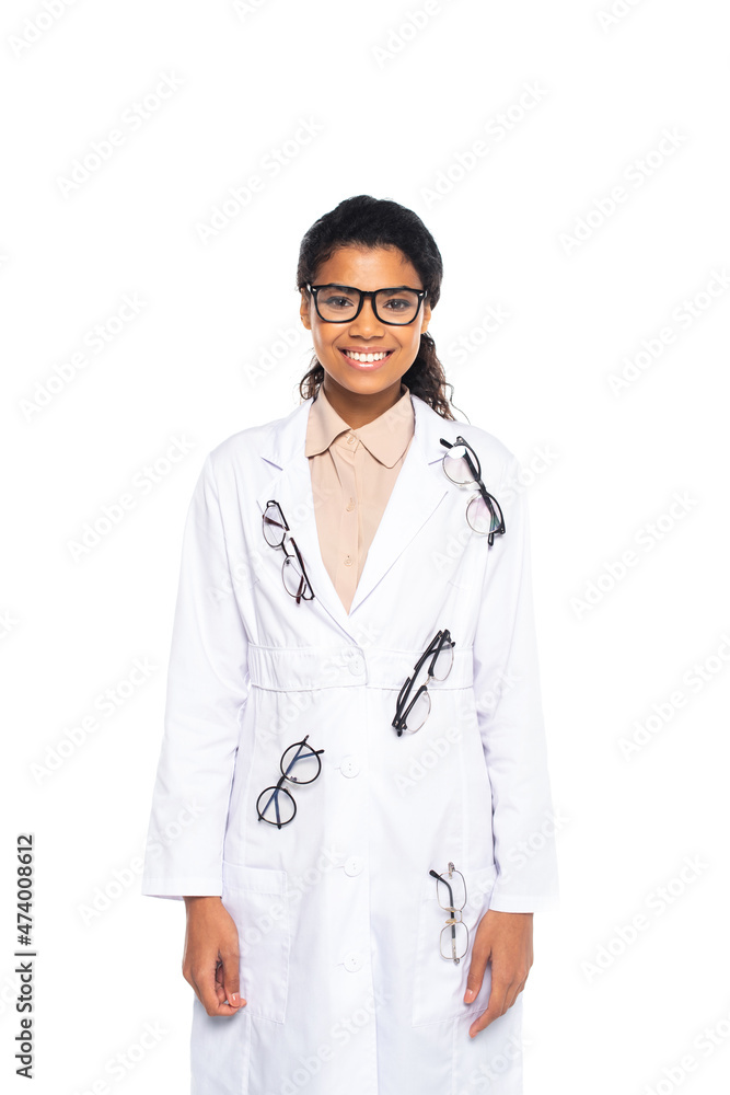 Smiling african american oculist in eyeglasses on coat looking at camera isolated on white. Smiling african american oculist in eyeglasses on coat looking at camera isolated on white.