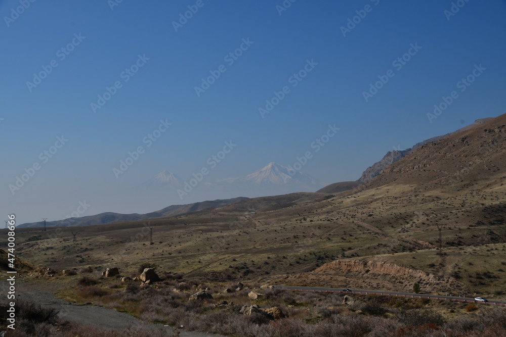 Autumn panorama of mountains and dirt road. Sunny day and cloudless sky.
