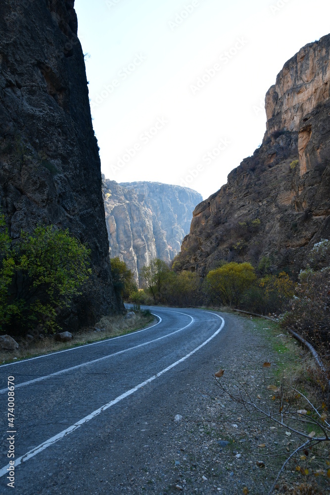 A car road in a deep mountain gorge. There are sheer cliffs along the road.