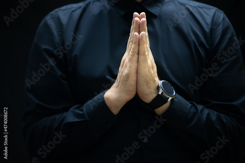 a man in a black shirt folded his hands in front of him and pleads for help for business