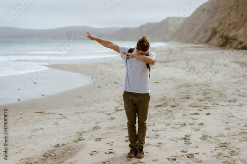 Young man dabbing while standing at beach at Point Reyes, California, USA photo