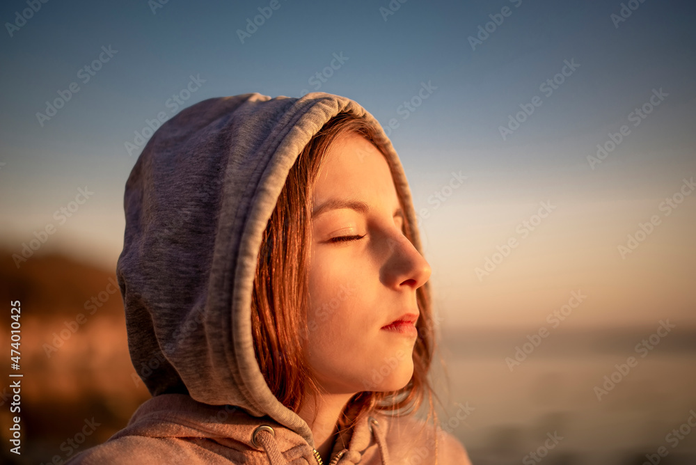 Germany, Mecklenburg-West Pomerania, Poel Island, Close-up of teenage girl with eyes closed on beach at sunset Germany, Mecklenburg-West Pomerania, Poel Island, Close-up of teenage girl with eyes closed on beach at sunset