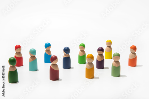Wooden people of different colors together on endless white background.