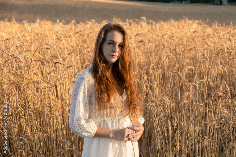 Redhead woman with wheat plant standing on field