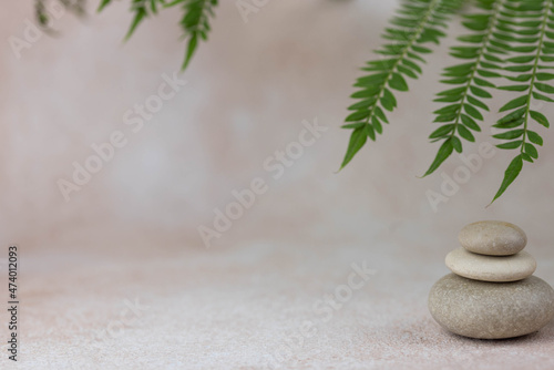 Canvas Print Pyramids of gray zen pebble meditation stones with green leaves on beige background