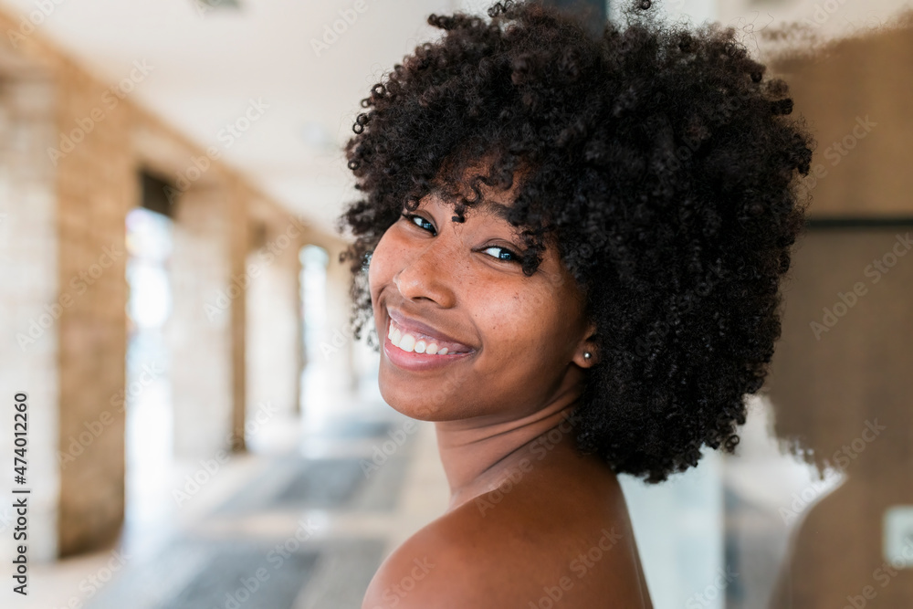 Smiling Afro woman looking over shoulder Smiling Afro woman looking over shoulder