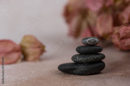 Pyramids of gray zen pebble meditation stones with green leaves on beige background. Concept of harmony, balance and meditation, spa, massage, relax.