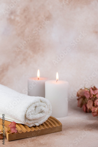 Spa still life treatment composition on massage table in wellness center. Twisted hot towel with aromatic candles on beige background. Aroma therapy setting. Concept of harmony, balance and meditation © strigana