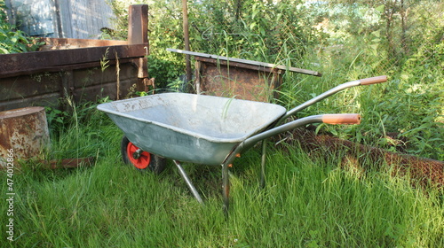 Garden wheelbarrow on green grass, rustic landscape