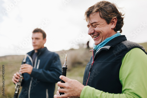 Happy man looking at musical instrument with male friend in background photo