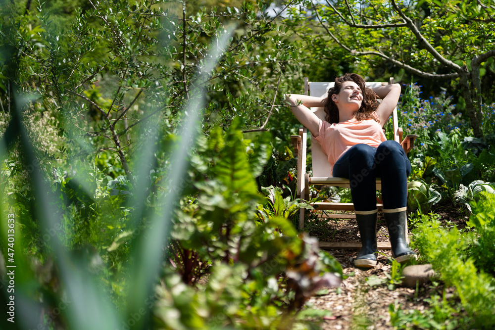 Young woman relaxing on chair in garden during sunny day Young woman relaxing on chair in garden during sunny day