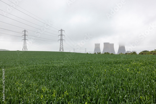 UK, England, Rugeley, Field with electricity pylons and cooling towers in background